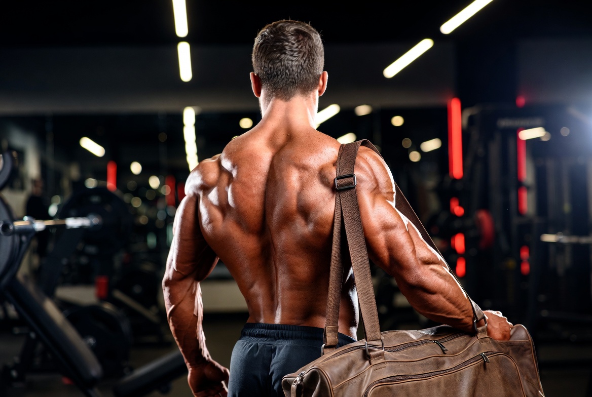 A muscular bodybuilder displaying clear, smooth skin across his shoulders and back inside a premium gym, highlighting the benefits of Ultima-Accutane 20mg for Sale.